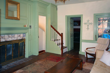 The living room, with built-in cabinets, wainscoting and a tile fireplace surround.